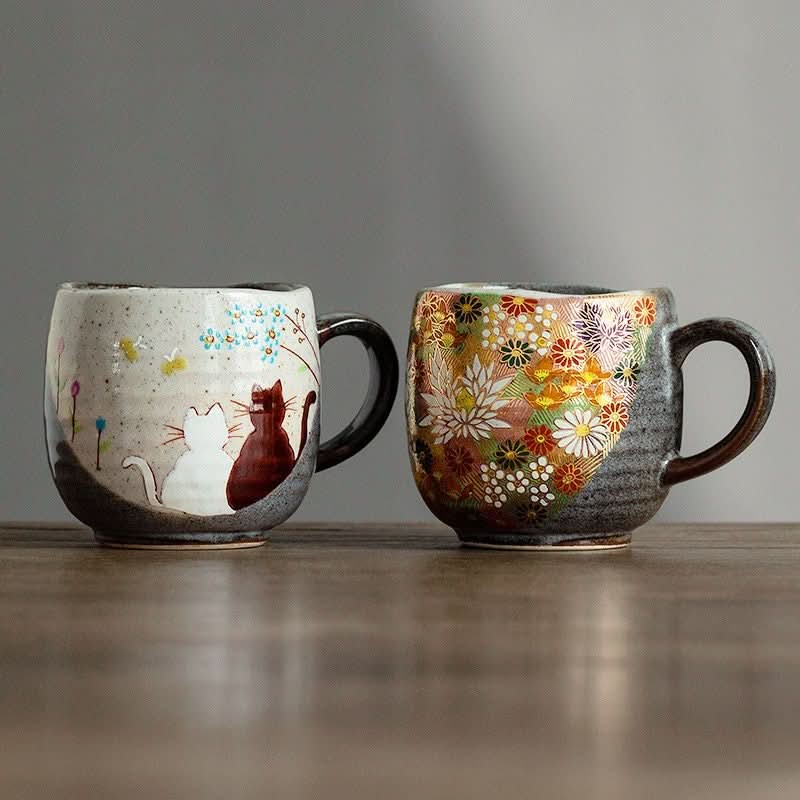Japanese Kutani-yaki stoneware mugs, one with cats, one with floral pattern.
